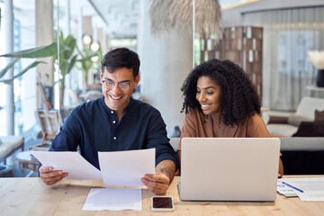 Professional business team of two diverse advisors, employees man and woman, manager and client talking using laptop computer discussing documents working in office at work meeting.
