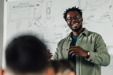 Smiling black male teacher explaining lesson to students in classroom
