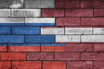 colourful painted big flag of russia and flag of latvia on a massive old brick wall background....