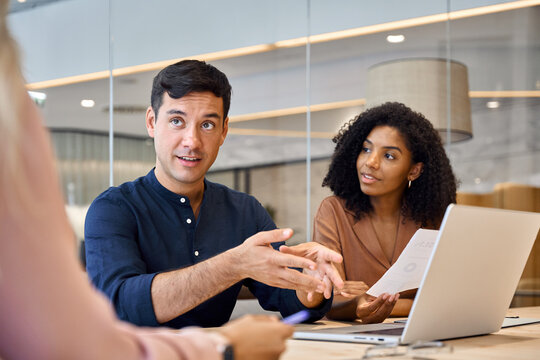 Happy young diverse people executive team working together at group meeting. Male professional manager discussing project plan with employees in office consulting clients on financial investment.