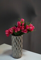 pink flowers in a mirror vase near the window