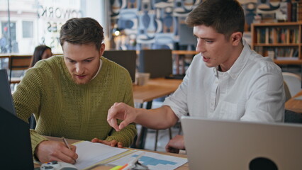 Young partners cooperating office boardroom discussing business ideas closeup