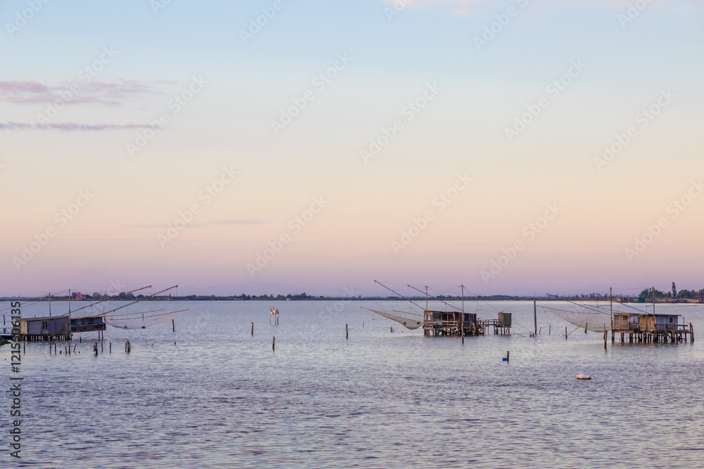 Wall mural Italy, Comacchio lagoon. Panorama with traditional house for fishing at sunset, blue sky