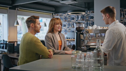 Businesspeople talking bartender ordering coffee at bar. People resting in cafe