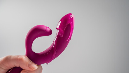 Lube pouring on pink dildo on white background. 