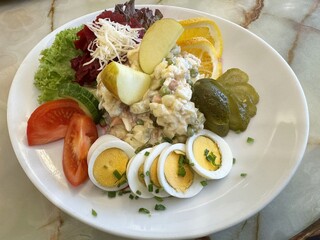 Fresh salad with egg slices, vegetables, and pickles on a white plate
