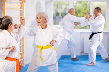 Intense oriental fight session, senior athletic practice combat karate techniques with male...