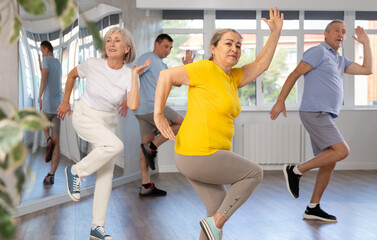 Fototapeta premium Group of aged people rehearsing sports dance in dance hall