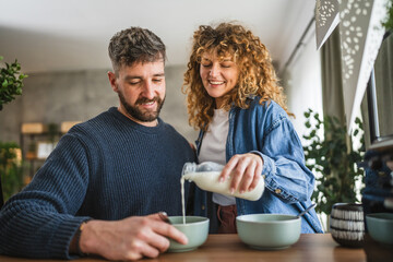 happy couple prepare oatmeal with milk for breakfast together at home