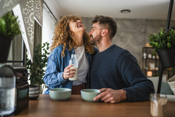 happy couple prepare oatmeal with milk for breakfast together at home