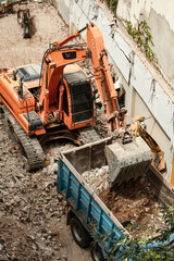 Excavator removing debris from a demolition site and dumping it into the truck