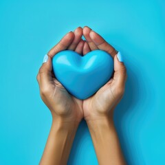 Obraz premium Female hands on a blue background holding a blue heart. The concept of donations and family insurance, World Heart Day. valentine's day.