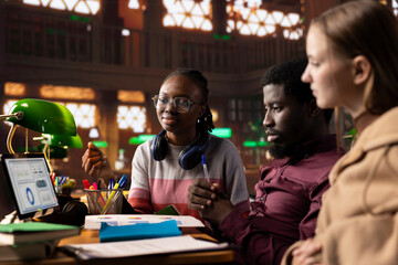 College students collaborating on a startup project in the campus library, focusing on international business administration and management. Studying hard for their academic degree.