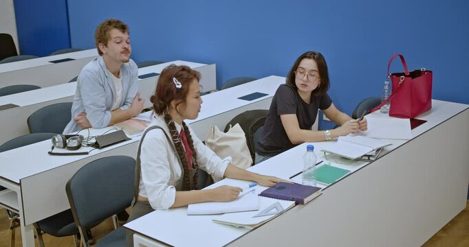 Students work diligently in a classroom setting, focusing on their individual tasks or exams. The professor walks around to provide assistance and support as needed.