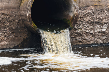 Dirty water flows from the pipe into the river, environmental pollution. Sewerage, treatment facilities
