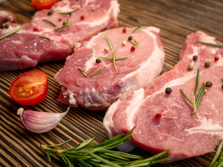 Fresh raw meat steak on a wooden board. Spices, garlic, rosemary, pepper, tomatoes.