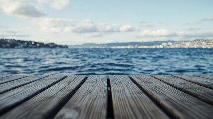 Calm waters stretch across the horizon from a wooden dock on a clear day near a coastal city