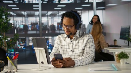 Executive assistant at a multinational company works with music on headphones, multitasking on business project. Professional uses data to manage operations and ensure successful outcome. Camera B.