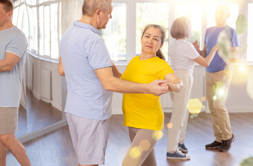 Fototapeta premium Group of elderly pensioners learn to dance a couple tango dance in a dance class