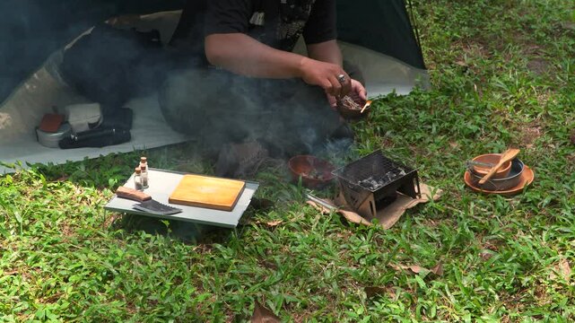 Close up of the activity of an Asian male adventurer cooking grilled shrimp using charcoal and wood. The bushcraft concept makes grilled shrimp with simple equipment in the lush wilderness