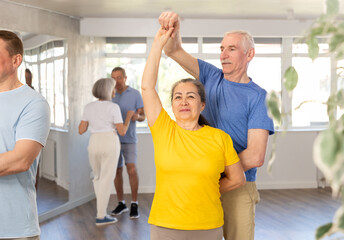 Couple of elderly man and elderly woman dancing waltz in studio