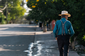 MEXICAN MAN ÎS WALKING WITH AN SOMBRERO IN THE THE STREETS OF BACALAR, MEXICO 