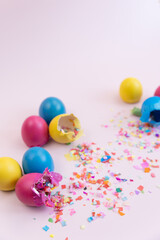 Colorful easter eggs broken with confetti on pink backdrop