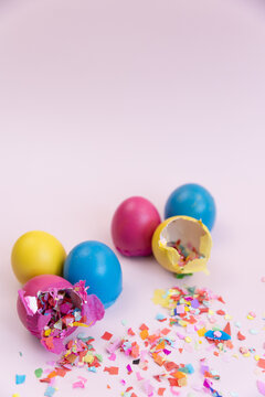 Colorful easter eggs broken with confetti on pink backdrop