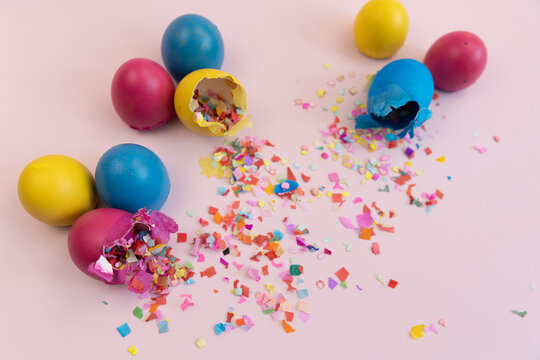 Colorful easter eggs broken with confetti on pink backdrop