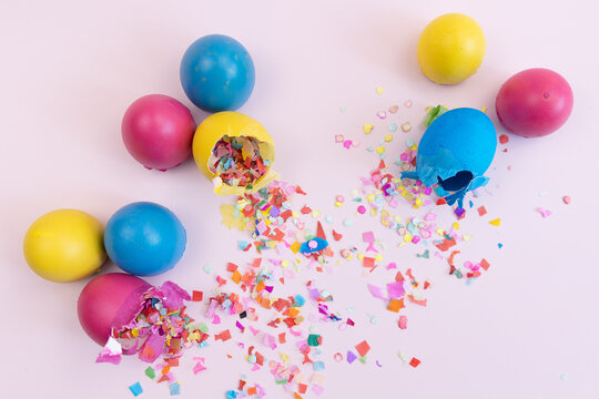 Colorful easter eggs broken with confetti on pink backdrop