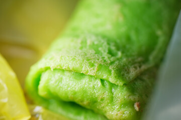 Coconut grated Pandan crepe know as Kuih Dadar. It is combination of sweet filling made from grated coconut and gula Melaka, wrapped in delicate, soft green crepes