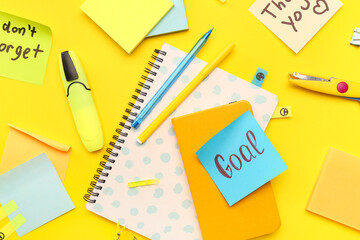 Sticky notes with notebooks and stationery on yellow background