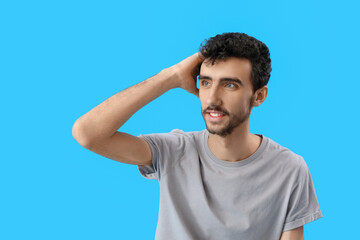 Young brunette man with stylish hairdo on blue background