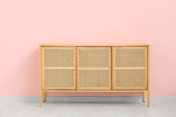 Wooden chest of drawers near pink wall in room