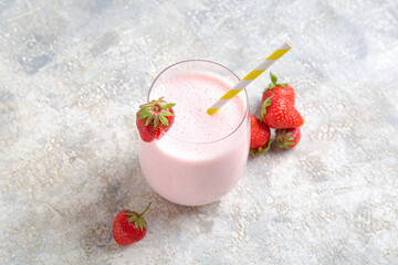 Glass of tasty strawberry smoothie on light background