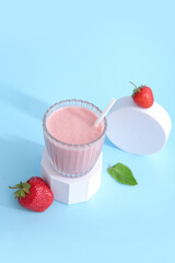Glass of tasty strawberry smoothie on blue background