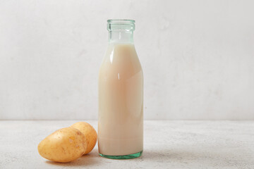 Bottle of tasty potato milk on light background