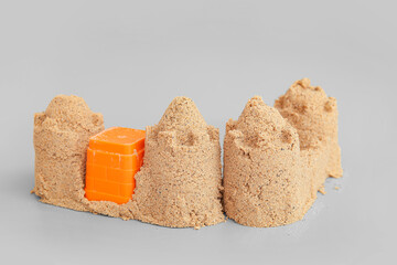 Castle made of sand with beach toy on grey background
