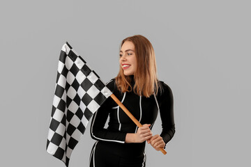 Happy young woman with racing flag on grey background