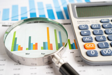 Magnifying glass with calculator on graph paper.