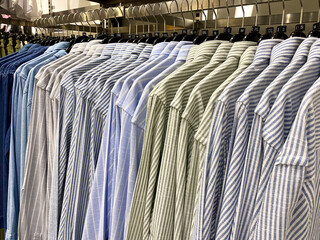 A row of shirts hangs neatly on a clothing rack in a close-up shot, showcasing a variety of colors and patterns