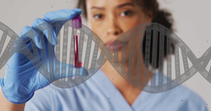 Image of dna strand and biracial female doctor with vial on white background