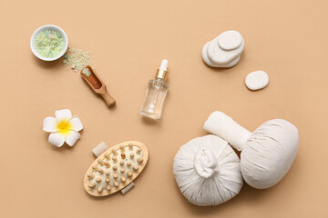 Obraz na płótnie Canvas Herbal bags, spa stones, massage body brush, bottle of cosmetic product and bowl with sea salt on beige background, closeup