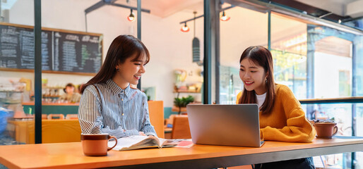Fototapeta premium おしゃれなカフェで勉強している二人の女子大学生。（Two female Asian college students studying in a stylish cafe.） 
