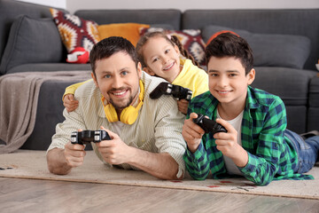 Happy father with his little children playing video game on floor at home