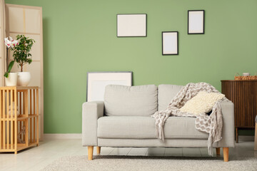 Stylish interior of modern living room with blank picture frames and comfortable sofa