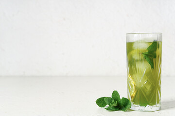 Glass of tasty lemonade and mint on white background