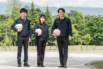 公園に立つ造園業・土木業の作業着姿の男女の作業員
