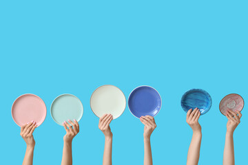 Hands holding empty plates on blue background