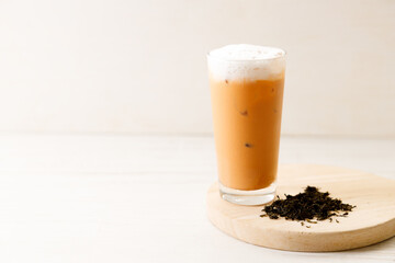 Iced Thai milk tea in a glass on wooden table.